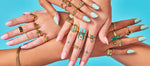 Multiple hands all wearing colorful gold rings
